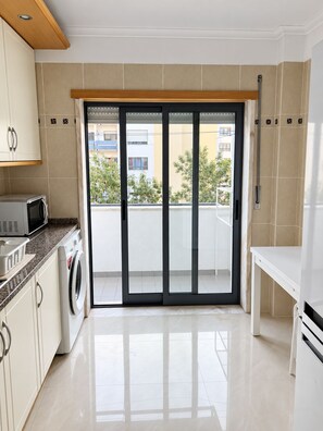 A modern kitchen with a washing machine, a microwave, and a sink. - Cavaleiros Premiun Stay (Santo António dos Cavaleiros)