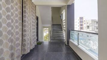 Un pasillo con cortinas estampadas, una escalera y un balcón con barandilla.