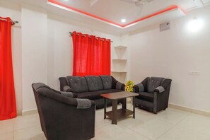 Una sala de estar con un sofá, dos sillones, una mesa de centro y una cortina roja.