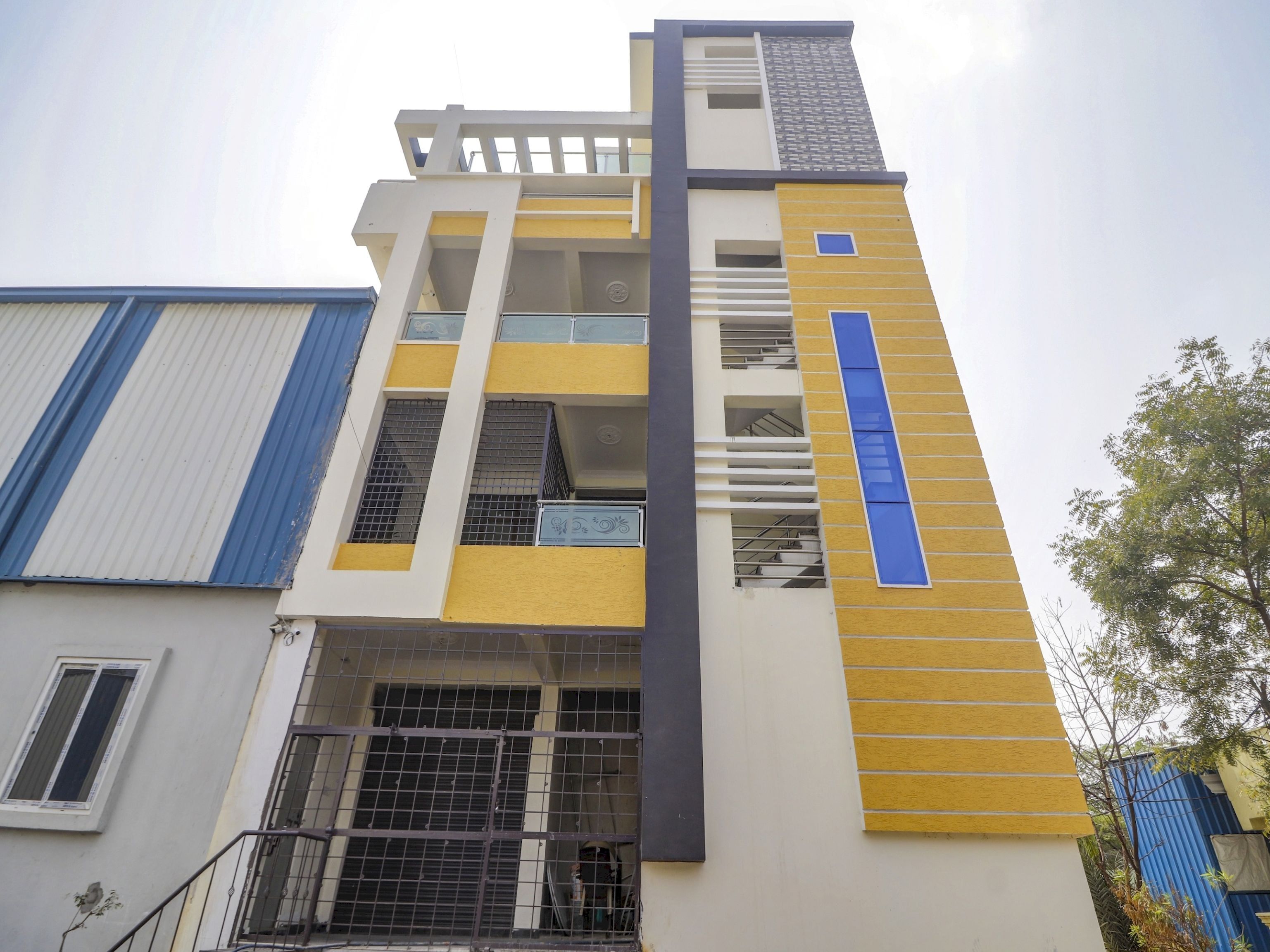 Un edificio de varios pisos con un diseño arquitectónico moderno, que combina colores amarillo y blanco, y una llamativa banda vertical azul.