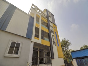 Un edificio de varios pisos con fachada plana, ventanas grandes y un balcón visible en el nivel superior.