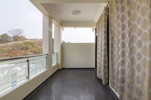 A balcony with a patterned curtain, a tiled floor, and a view of the landscape. - Hotel O Home RBS Homes (Hyderabad)