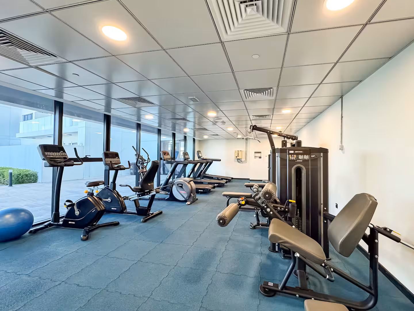 A gym with cardio machines, weightlifting equipment, and exercise balls.