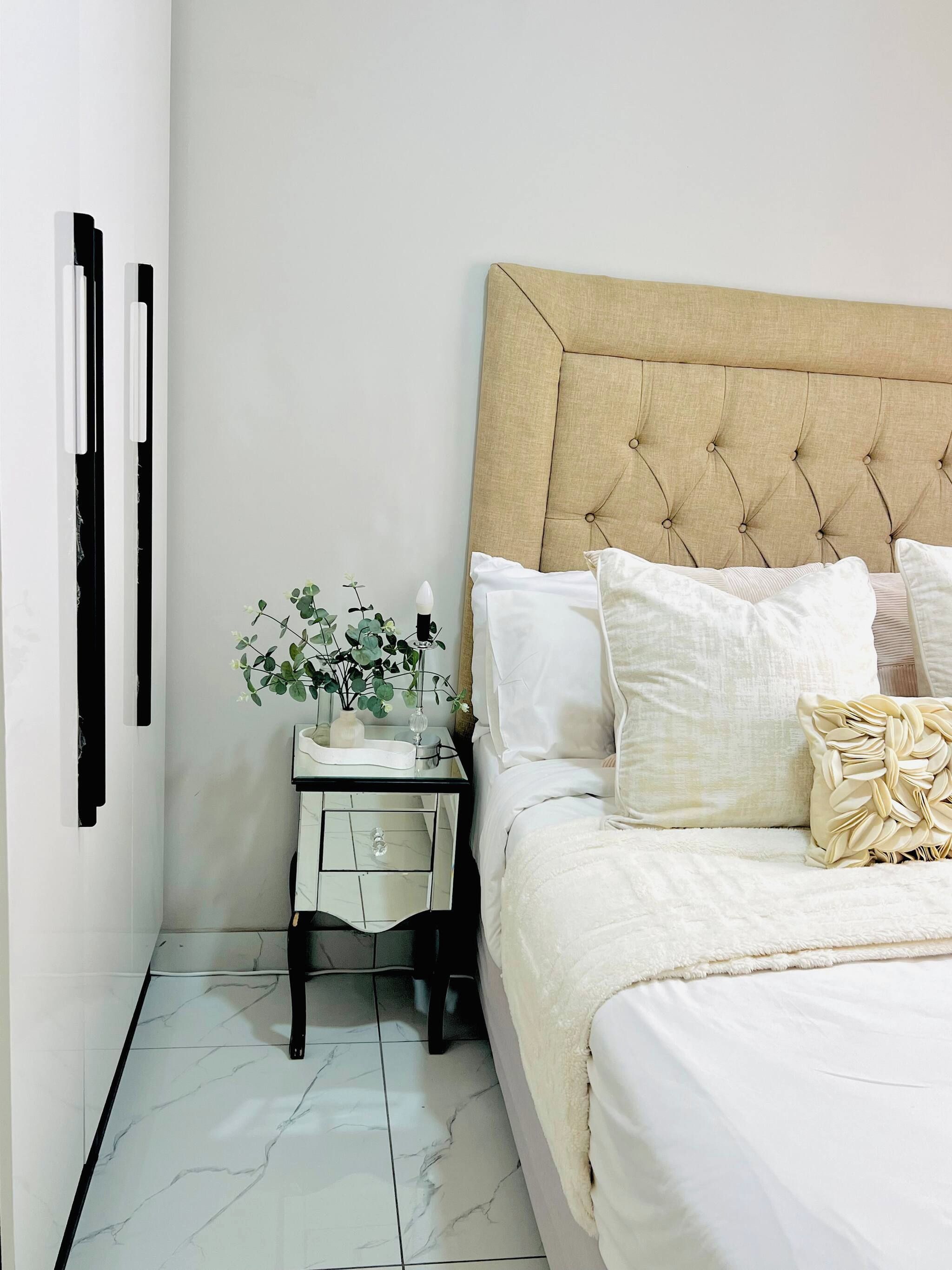 A neatly arranged bedroom with a bed, bedside table, and a potted plant.
