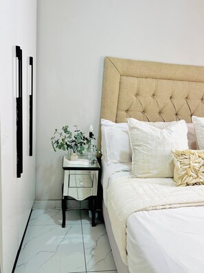 A neatly arranged bedroom with a bed, bedside table, and a potted plant.