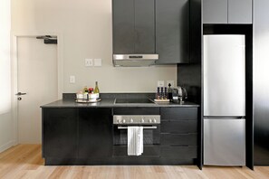 Una cuina moderna amb forn encastrat, nevera d'acer inoxidable i encimera negra.