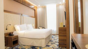 Ein Hotelzimmer mit Bett, Nachttisch, Lampe und Spiegel.
