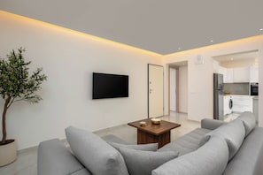 A modern living room with a flat-screen TV, a coffee table, and a grey sofa. - Annamaria's Apartment (Rodos)