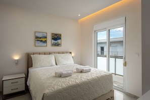 A bedroom with a bed, two pillows, a nightstand, a wall-mounted light, and two framed pictures. - Annamaria's Apartment (Rodos)
