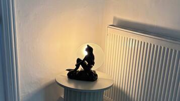 A corner room with a radiator, a small round table with a sculpture, and a carpeted floor.