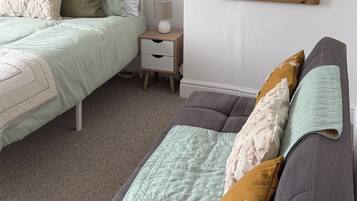 A bedroom with a bed, bedside table, lamp, and a large mirror on the wall.