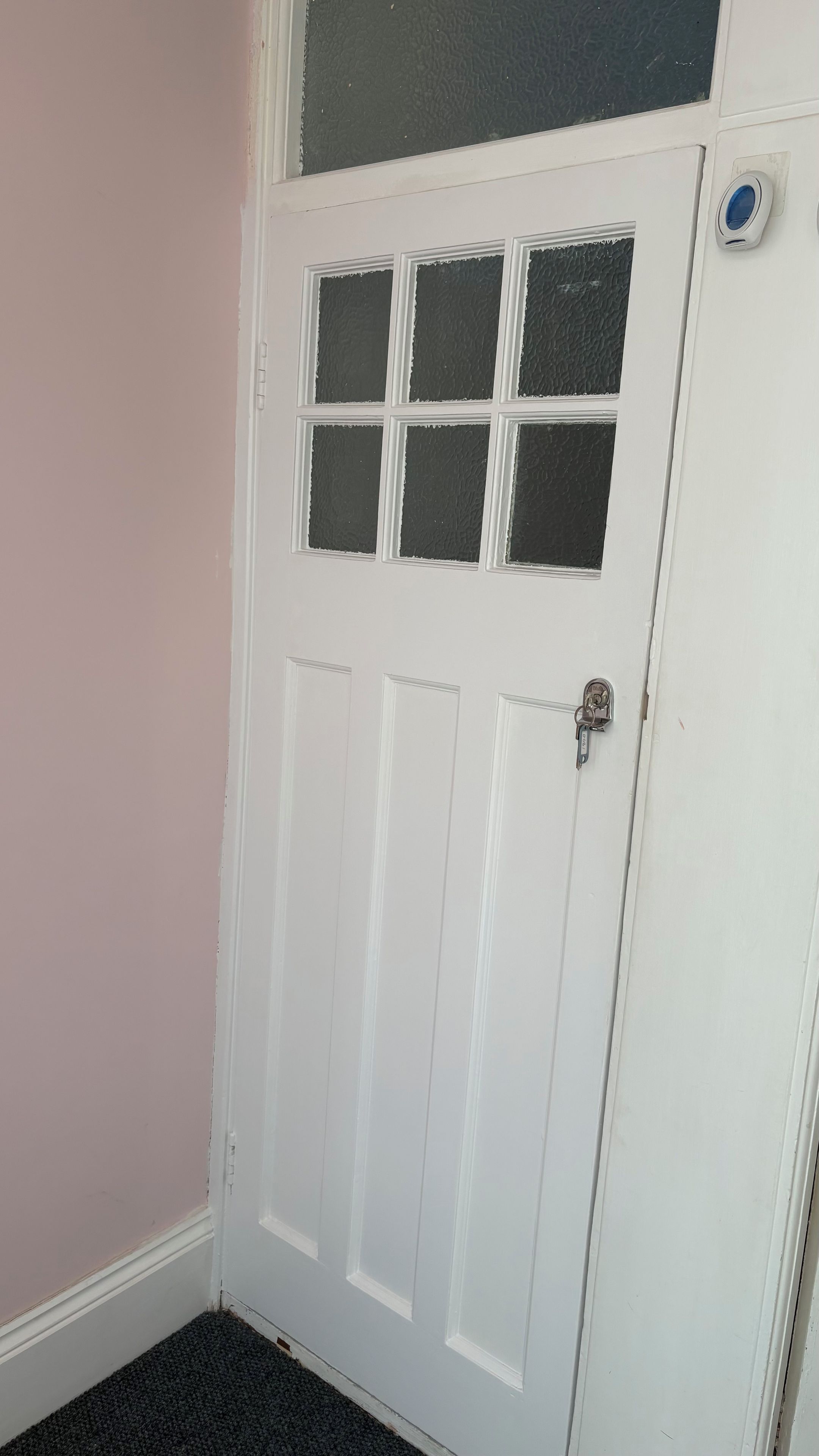 A white door with a small window and a peephole.