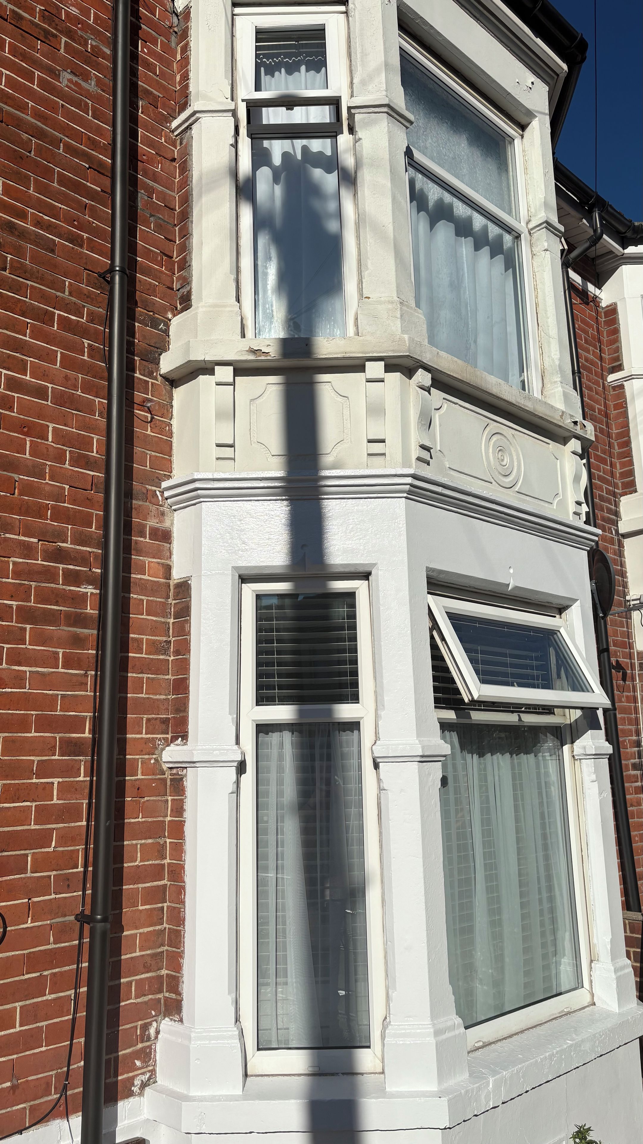 A corner of a building with a brick facade and white-painted trim around windows and a door.