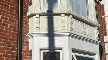 A corner of a building with a brick facade and white-painted trim around windows and a door.