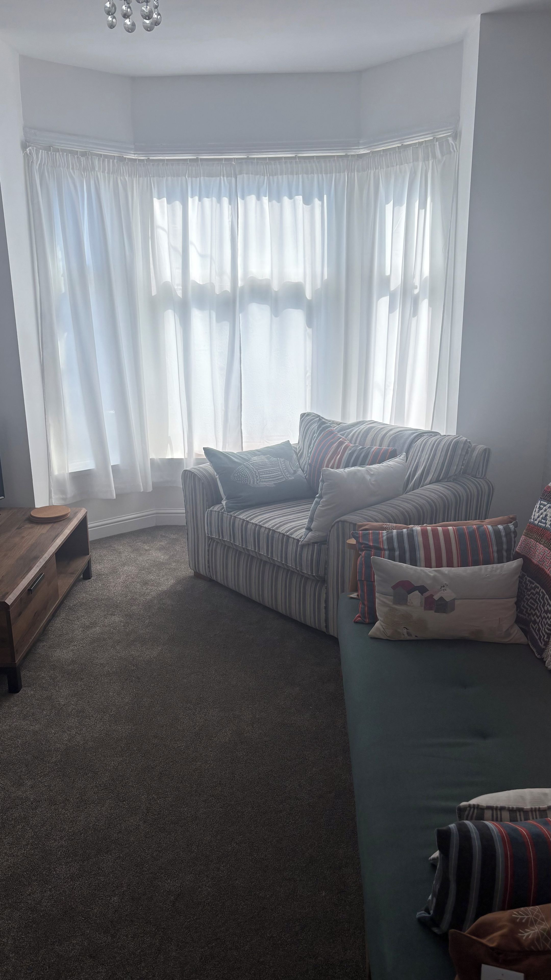 A living room with a striped sofa, a green couch, and a wooden coffee table.