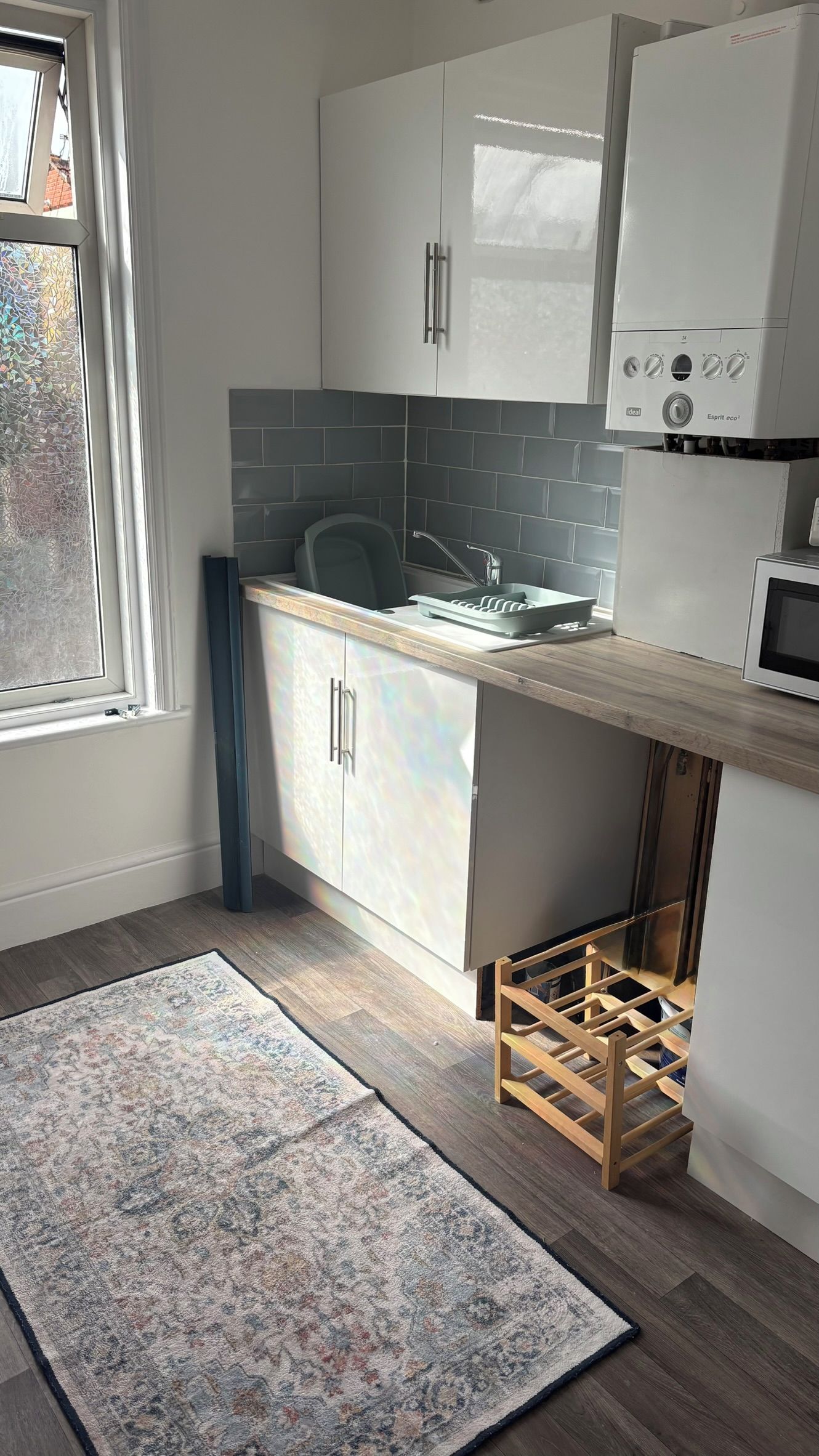 A modern kitchen with white cabinets, a grey backsplash, and a built-in microwave.