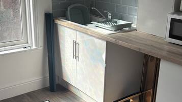 A modern kitchen with white cabinets, a grey backsplash, and a built-in microwave.