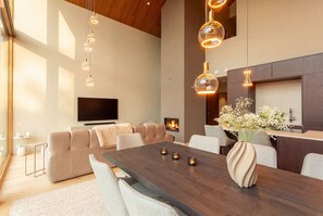Una sala de estar moderna con un amplio comedor de madera, sofás y una chimenea.