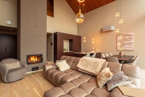A modern living room with a fireplace, a sectional sofa, and a dining area. - Stay North: Joiku - Kiruma (Kolari)