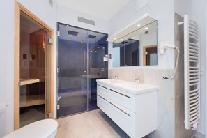 A modern bathroom with a glass shower enclosure, a white vanity with a mirror, and a built-in towel rack. - Promenadenvilla 23, Apartment 07 (Lübeck-Travemünde)