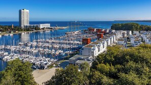 Uma marina com vários barcos atracados, cercada por edifícios modernos e uma vista clara do mar.