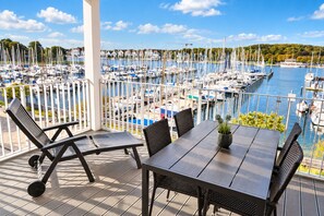 A terrace with a table and chairs overlooking a marina with numerous boats. - Promenadenvilla 23, Apartment 07 (Lübeck-Travemünde)