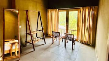 A room with a high ceiling, a wooden ladder, a wooden bench, and a window with curtains.
