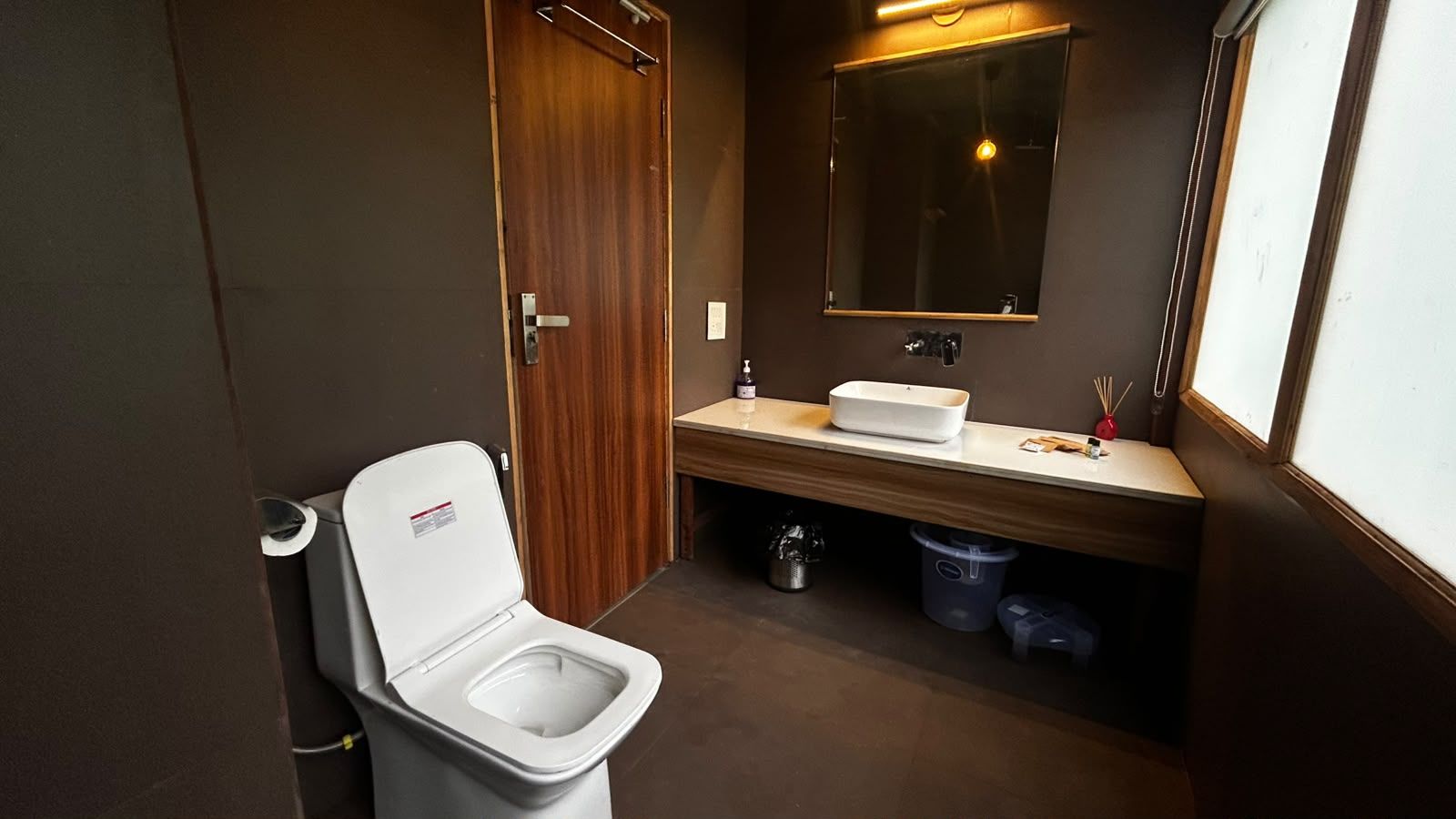 A small, compact bathroom with a toilet, sink, and mirror.
