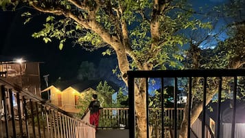 Un cancello chiuso con una scala in legno che conduce a un edificio, circondato da alberi e da un cielo notturno.
