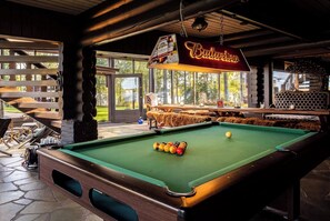 Ein Billardtisch mit Kugeln, eine Neonreklame für Budweiser und Blick ins Freie.