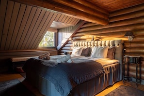 Ein Schlafzimmer in einer Blockhütte mit einem großen Bett, einer Bank und einer Lampe.