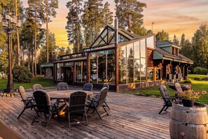 Ein modernes Haus mit einer Terrasse, Sitzgelegenheiten im Freien und Blick auf den umliegenden Wald.