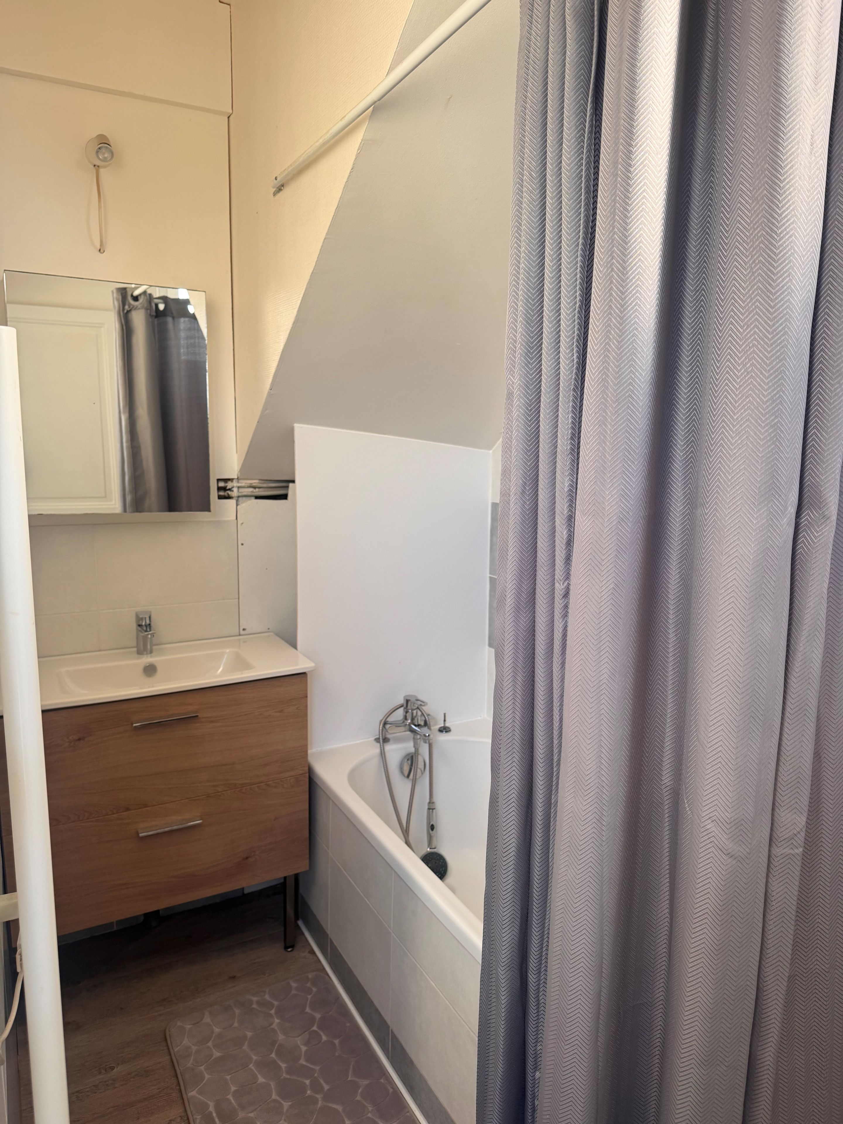 Une salle de bain avec un lavabo blanc, un meuble-lavabo en bois et une baignoire.