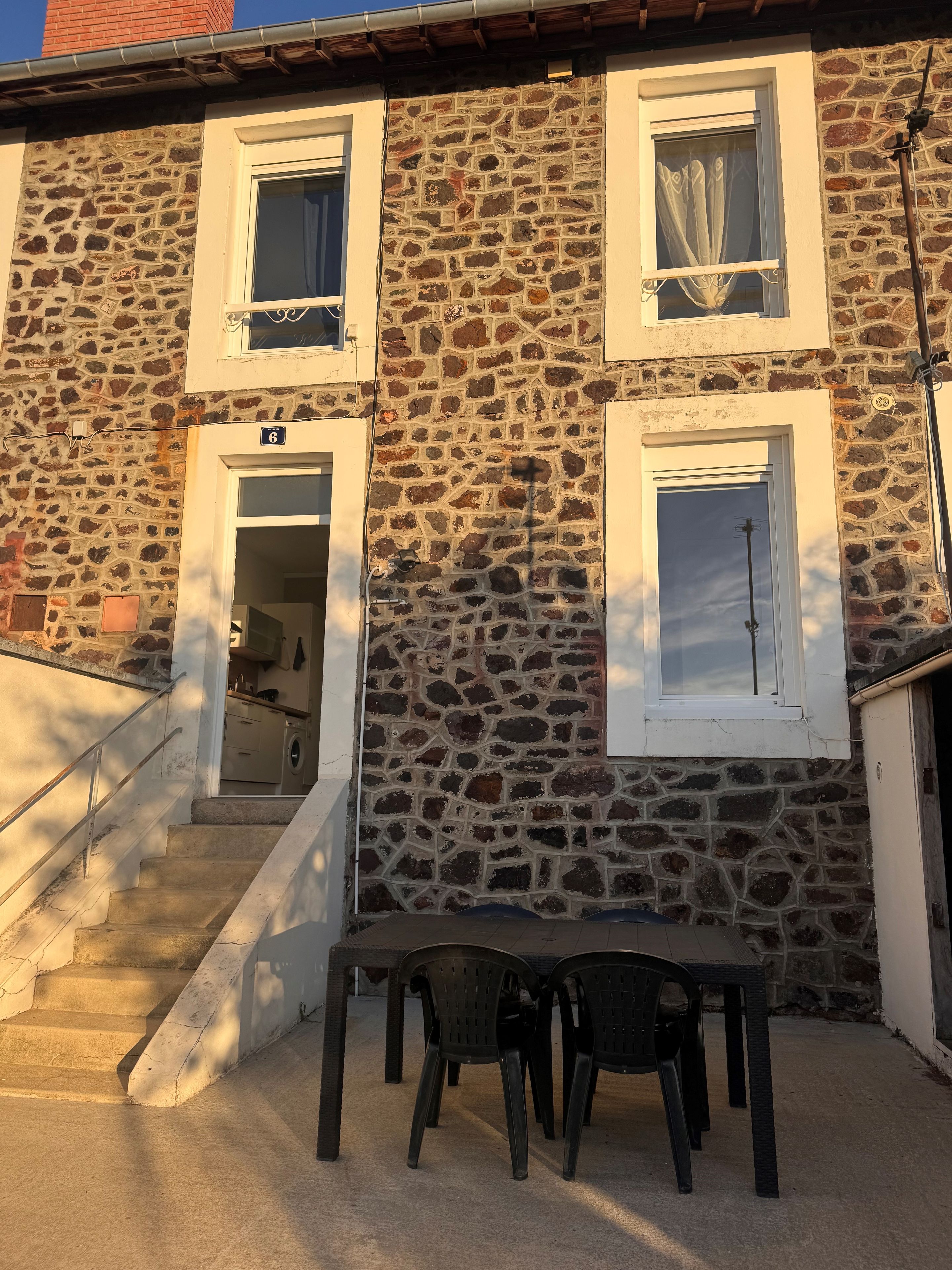Un bâtiment en pierre avec un escalier menant à une porte portant le numéro 6.