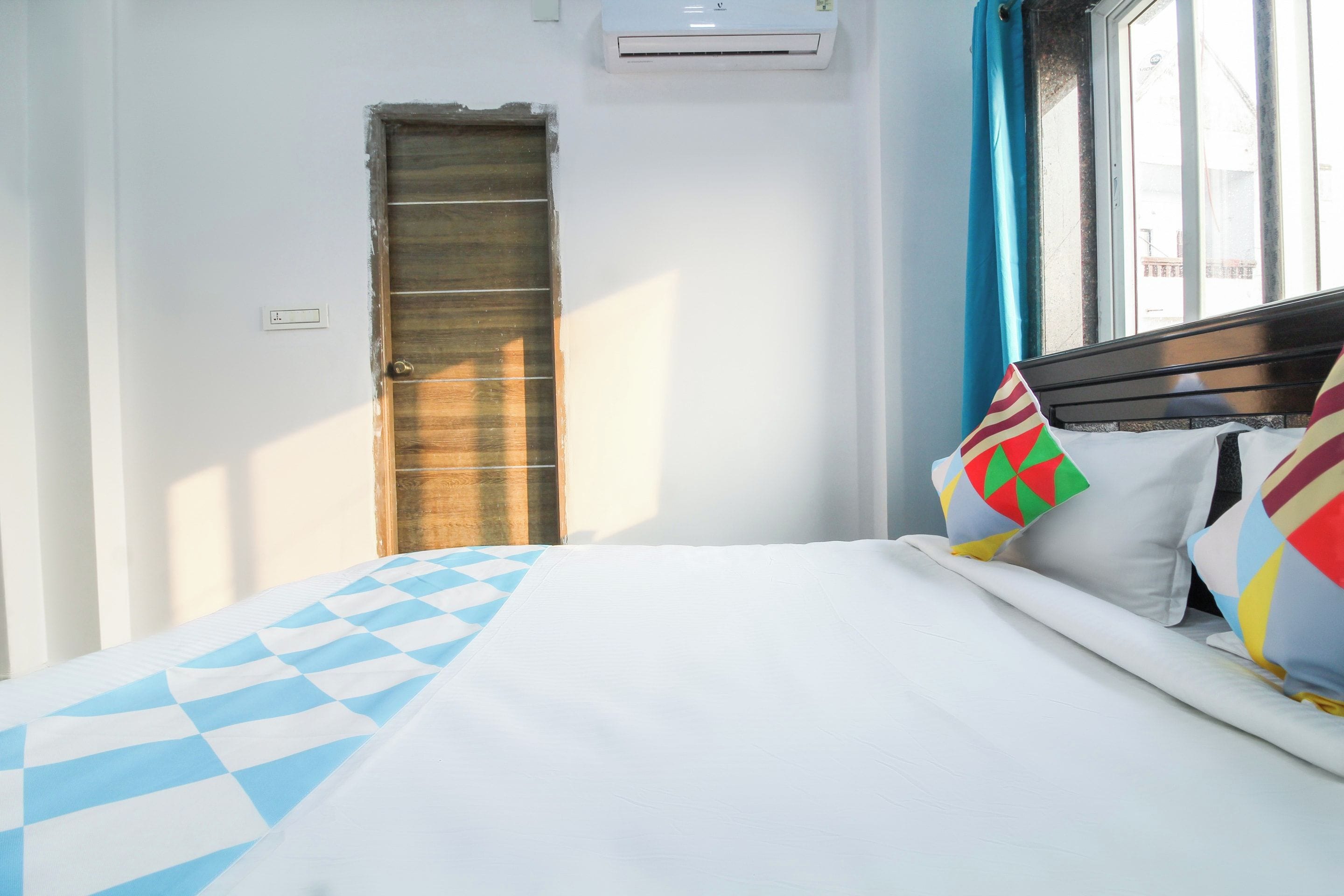 Ein Hotelzimmer mit einem Bett, einer Holztür und einem Fenster mit Vorhängen.