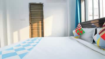 Ein Hotelzimmer mit einem Bett, einer Holztür und einem Fenster mit Vorhängen.