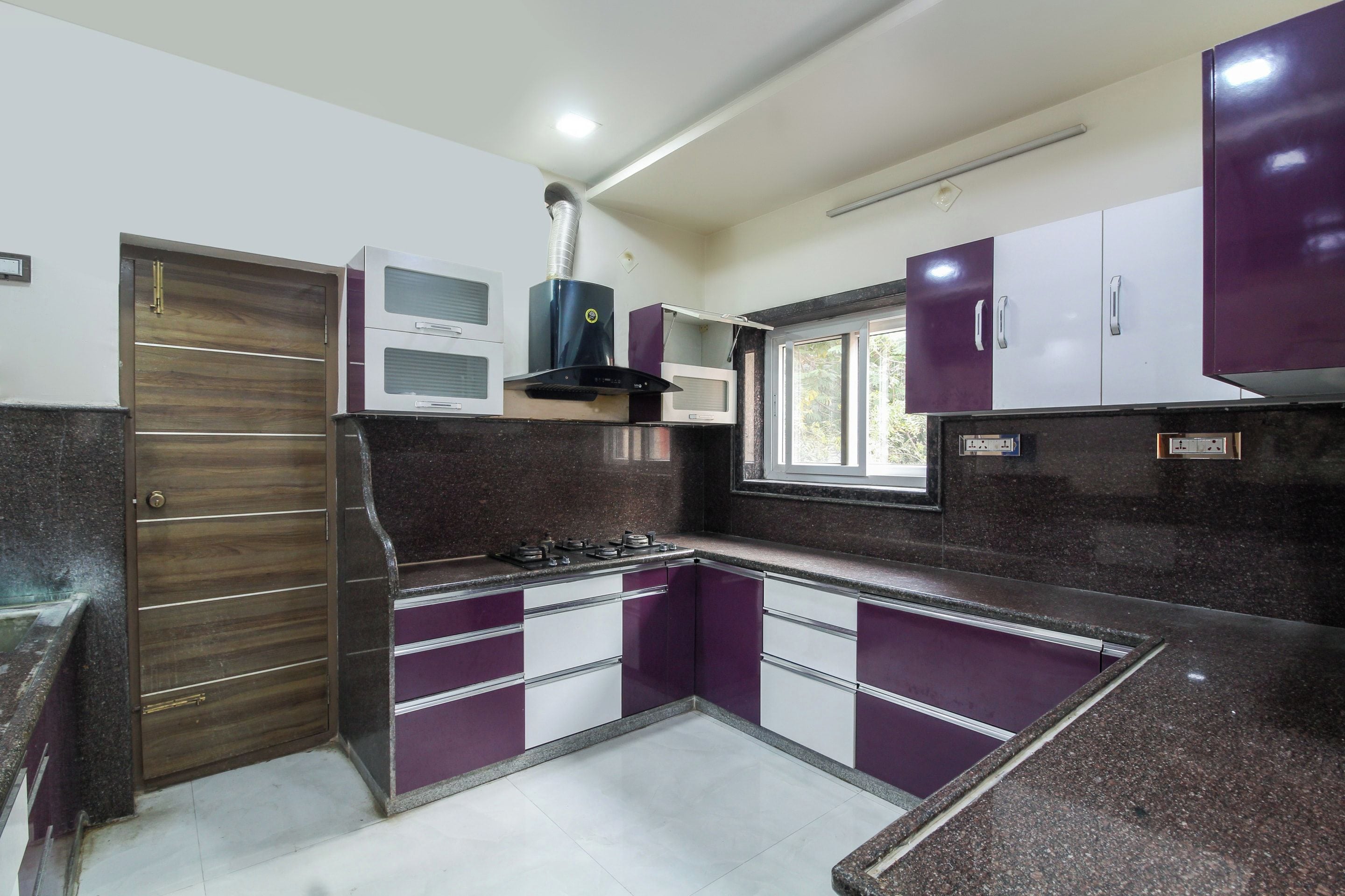 Una cocina con estufa integrada, armarios y una ventana.