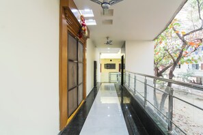 A corridor with a glass railing, a ceiling fan, and a view of the outside. - Hotel O Home Dk Homes (Hyderabad)