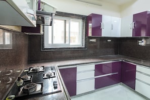 A kitchen with a gas stove, cabinets, and a window. - Hotel O Home Dk Homes (Hyderabad)