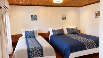 Habitación de hotel con dos camas, suelo y techo de madera.