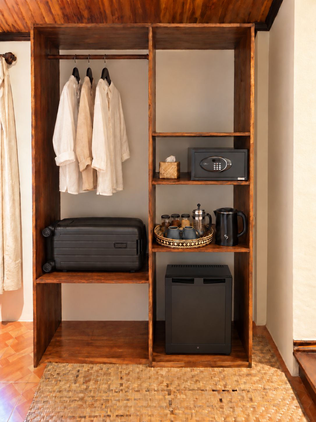 Ein Holzkleiderschrank mit Kleidung, ein Safe, ein Tablett mit Küchenutensilien und ein schwarzes Koffer.