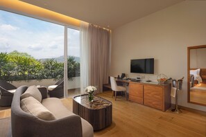 A modern living room with a sofa, a coffee table, a TV, and a desk with a computer.