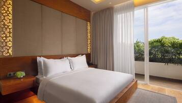 A modern hotel room with a large bed, a wooden headboard, a bedside table with a phone, and a view of greenery through the window.