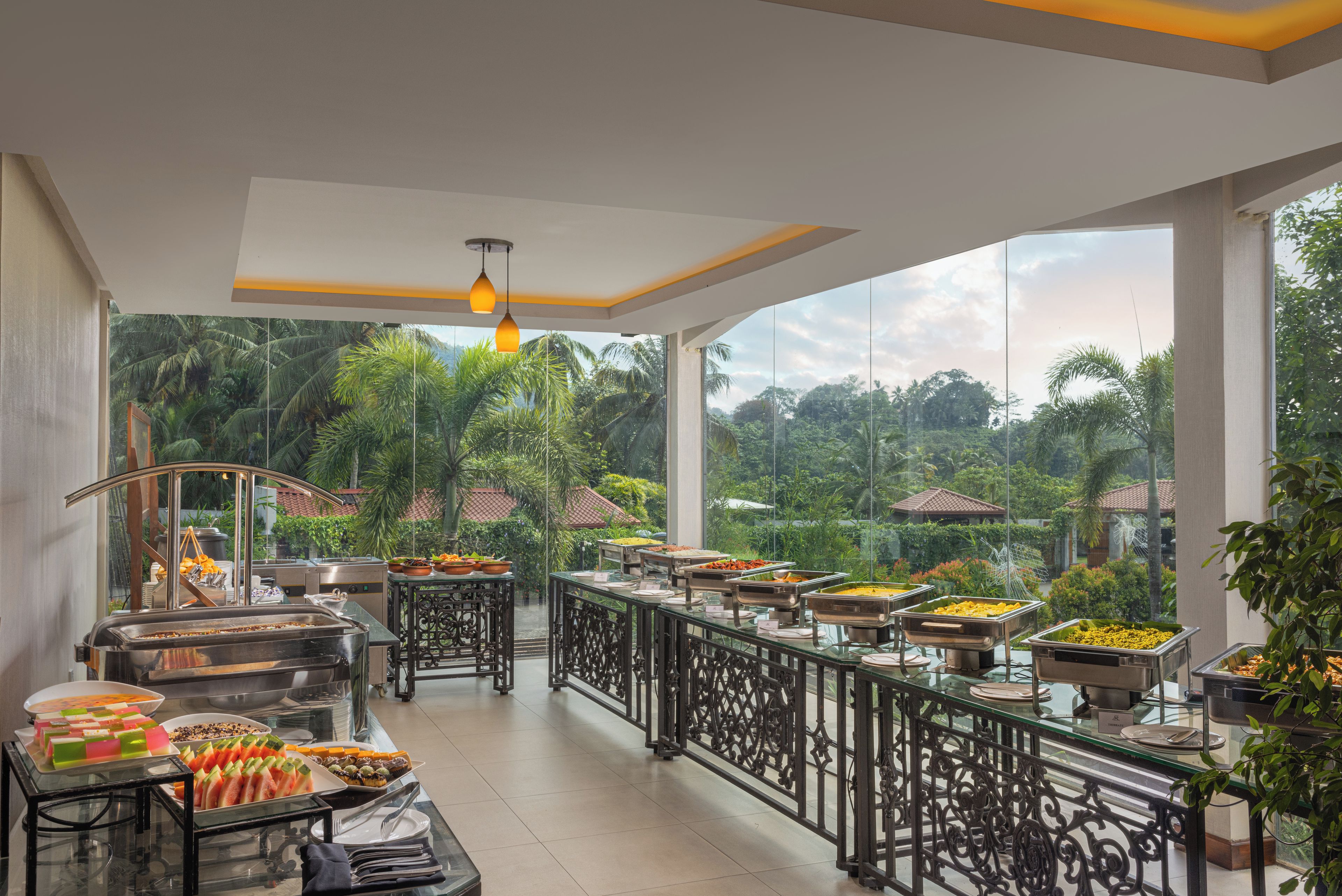 A buffet setup with various food items and a view of a lush garden.