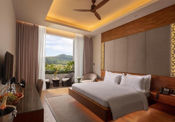 A hotel room with a large bed, a desk with a chair, a television, and a view of the outdoors.
