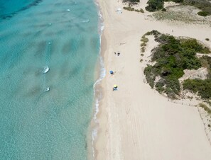An aerial view of a beach with clear turquoise waters, a sandy shore, and sparse vegetation. - Cala Doré Garden Stay Vicino al Mare di Punta Prosciutto (Porto Cesareo)