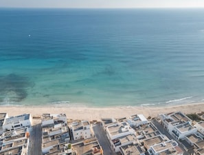 An aerial view of a coastal town with buildings along the beachfront and the ocean in the background. - Cala Doré Garden Stay Vicino al Mare di Punta Prosciutto (Porto Cesareo)