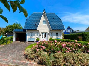 A two-story house with a steeply pitched roof, a front porch, and a garage. - Friesenhaus for 4 – Baltic Sea Bliss for the Whole Family (Schönberg (Holstein))