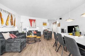 Un saló modern amb un sofà gris, una taula de centre i una zona de dinar amb cadirees i una taula.