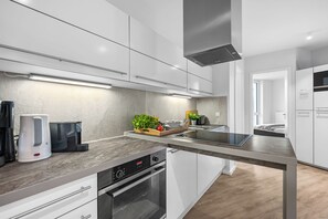 Een moderne keuken met witte kastjes, een roestvrijstalen aanrechtblad en een ingebouwde oven.